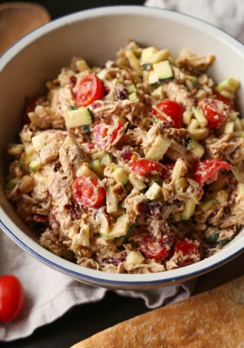 A crunchy salad composed of veggies, flavorings and shredded rotisserie chicken inside of an off-white bowl