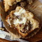 A banana muffin split in half on a liner spread with butter