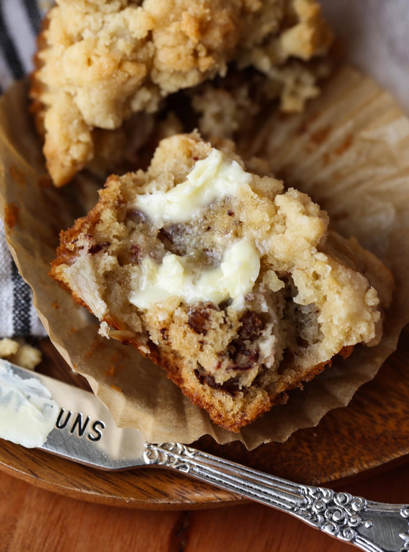 A banana muffin split in half on a liner spread with butter