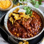 Chili in a bowl topped with Fritos and Sour Cream