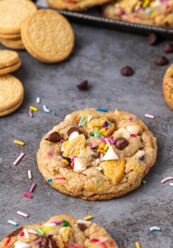 A birthday cake chocolate chip cookie on a countertop, surrounded by more cookies.