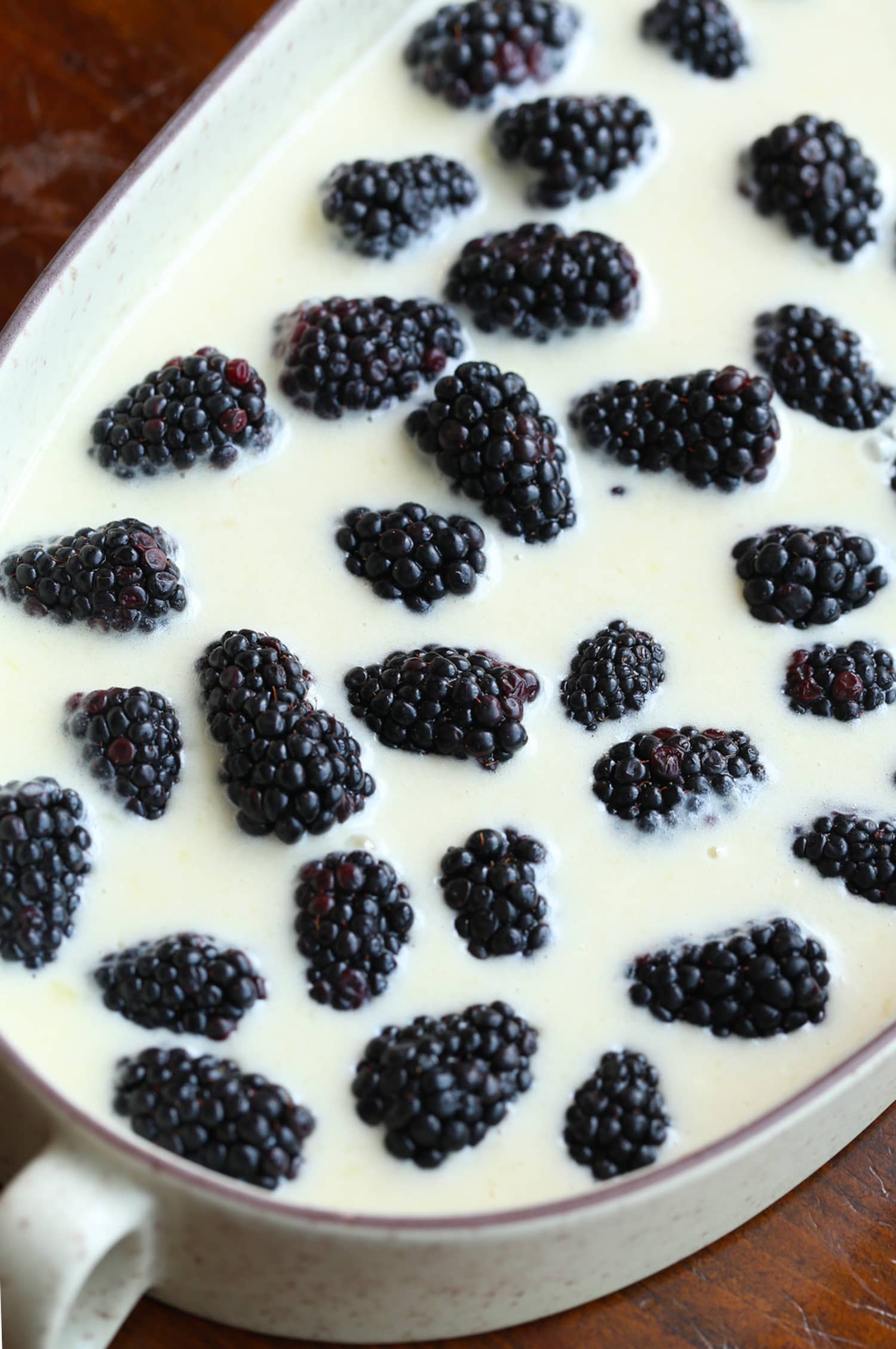 Easy cobbler batter in a casserole baking dish with blackberries before going in the oven