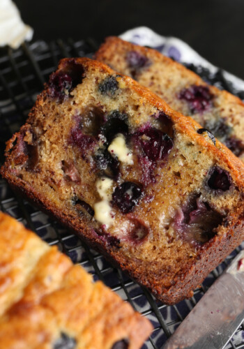 Slices of homemade blueberry banana bread laying next to a loaf.