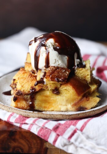 Bread pudding plated and then toped with vanilla ice cream and chocolate syrup