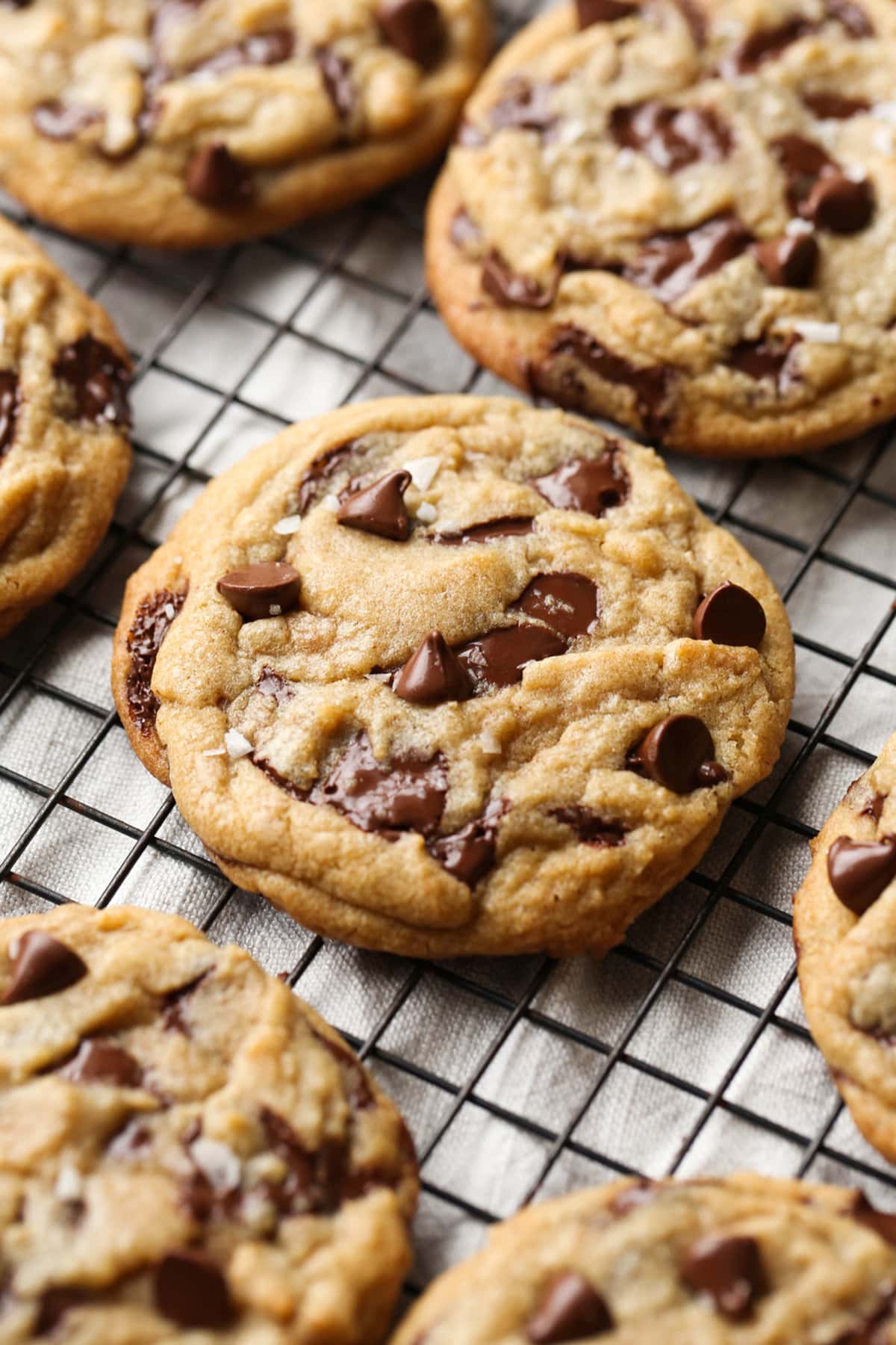 Brown Butter Chocolate Chip Cookies topped with flaked sea salt on a wire cooling rack