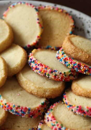 Plate of butter cookies with their edges coated with sprinkles.