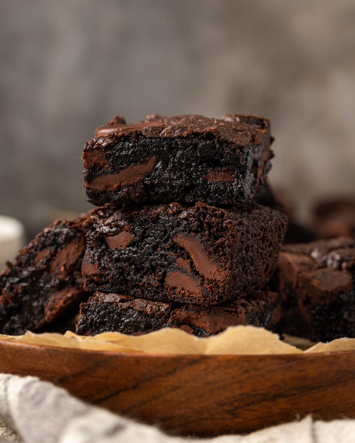 A stack of fudgy cake mix brownies on a plate lined with parchment paper.