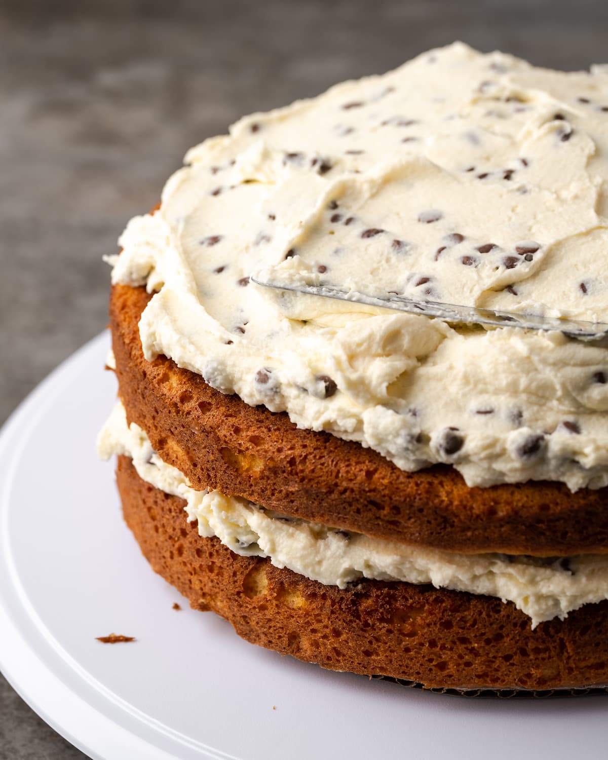 Assembled, unfrosted cannoli cake showing the layers of vanilla cake and cream filling.