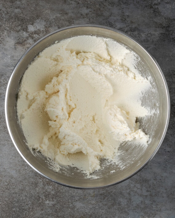 Vanilla frosting in a metal mixing bowl.