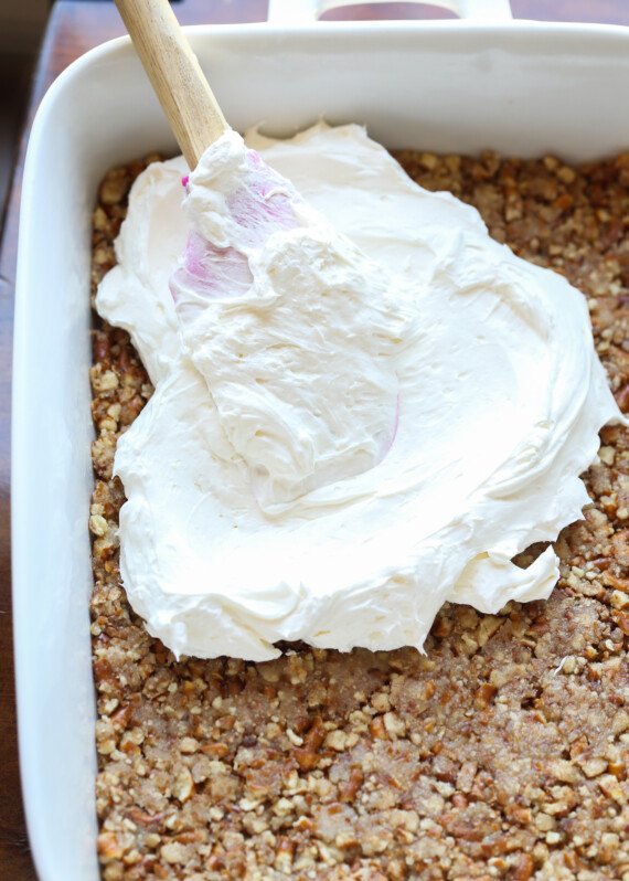 spreading whipped cream on a pretzel crust