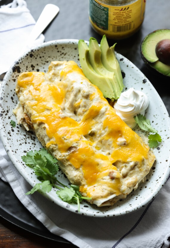 2 chicken enchiladas on a stoneware plate covered in cheese