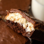 Close up of a coconut brownie leaning against another brownie, showing the coconut layer.