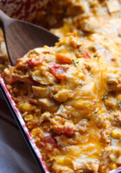 A serving spoon scooping into a baked fiesta chicken casserole.