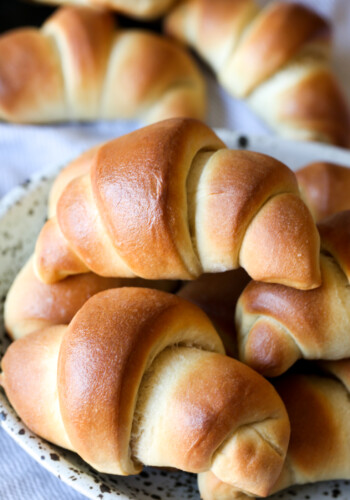 An assortment of golden baked crescent rolls on a plate.