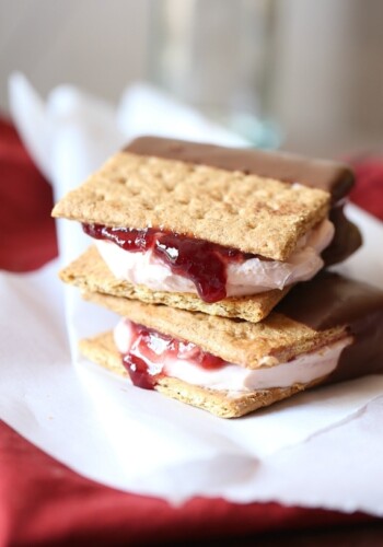 Two Chocolate Dipped Strawberry Cheesecake Sandwiches stacked on a white cloth.