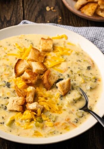 A bowl of instant pot broccoli cheddar soup topped with croutons with a spoon.