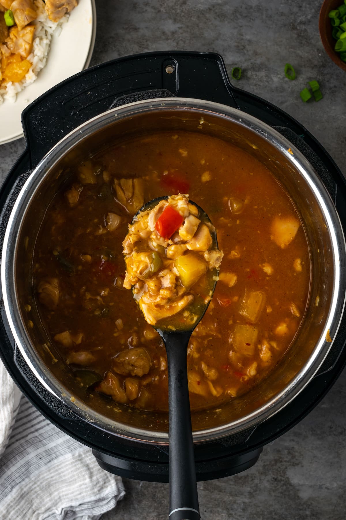 Overhead view of a spoonful of Hawaiian chicken held over the Instant Pot.