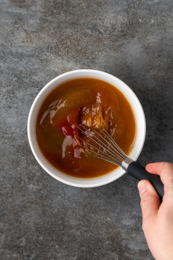 Pineapple juice is whisked into the sauce for Hawaiian chicken a white bowl.