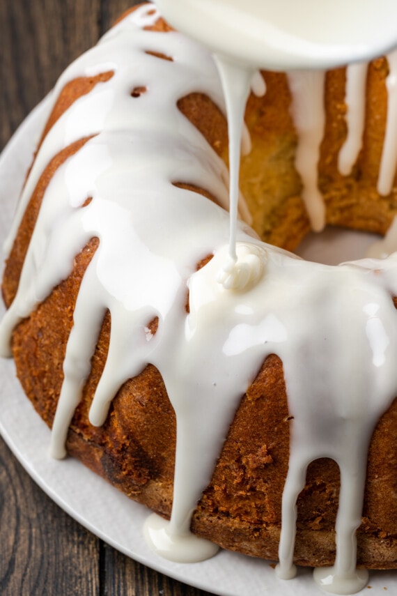 Close up view of icing as its drizzled over a full Key lime pound cake.