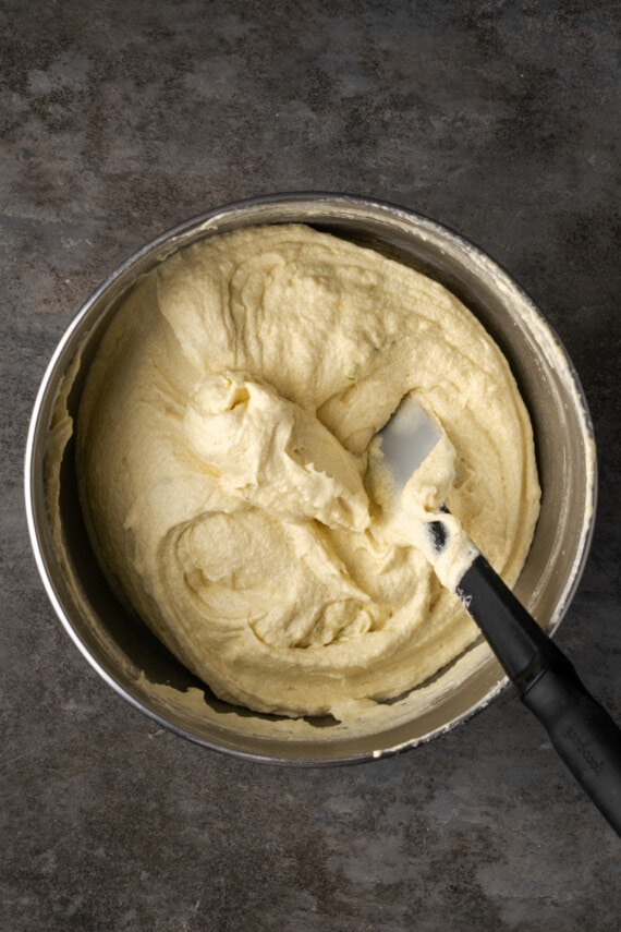 Key lime pound cake batter in a metal bowl with a stirring spoon.