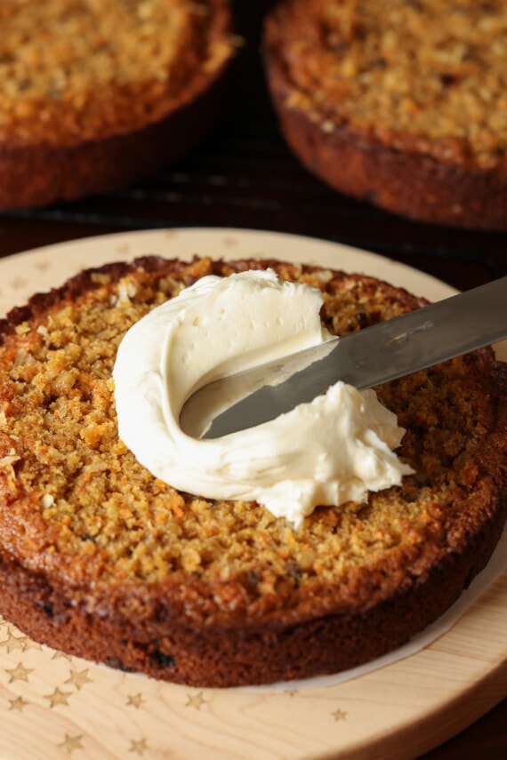 spreading cream cheese frosting on a layer of cake with an offset spatula