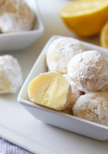 A small bowl of white chocolate lemon truffles, with one truffle cut in half.