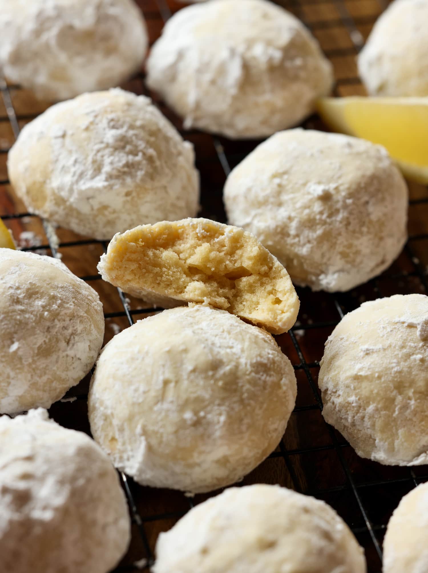 Lemon cookie coated in powdered sugar broken in half on a cooling rack