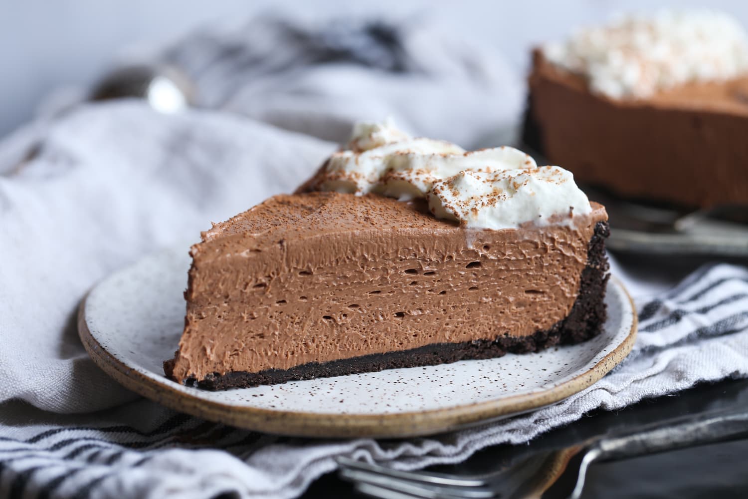 A slice of Nutella cheesecake with Oreo crust and whipped cream.