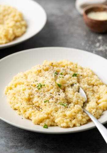 Pastina served on a white plate topped with black pepper and parmesan.