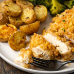 Sliced chicken on a plate with potatoes and broccoli.