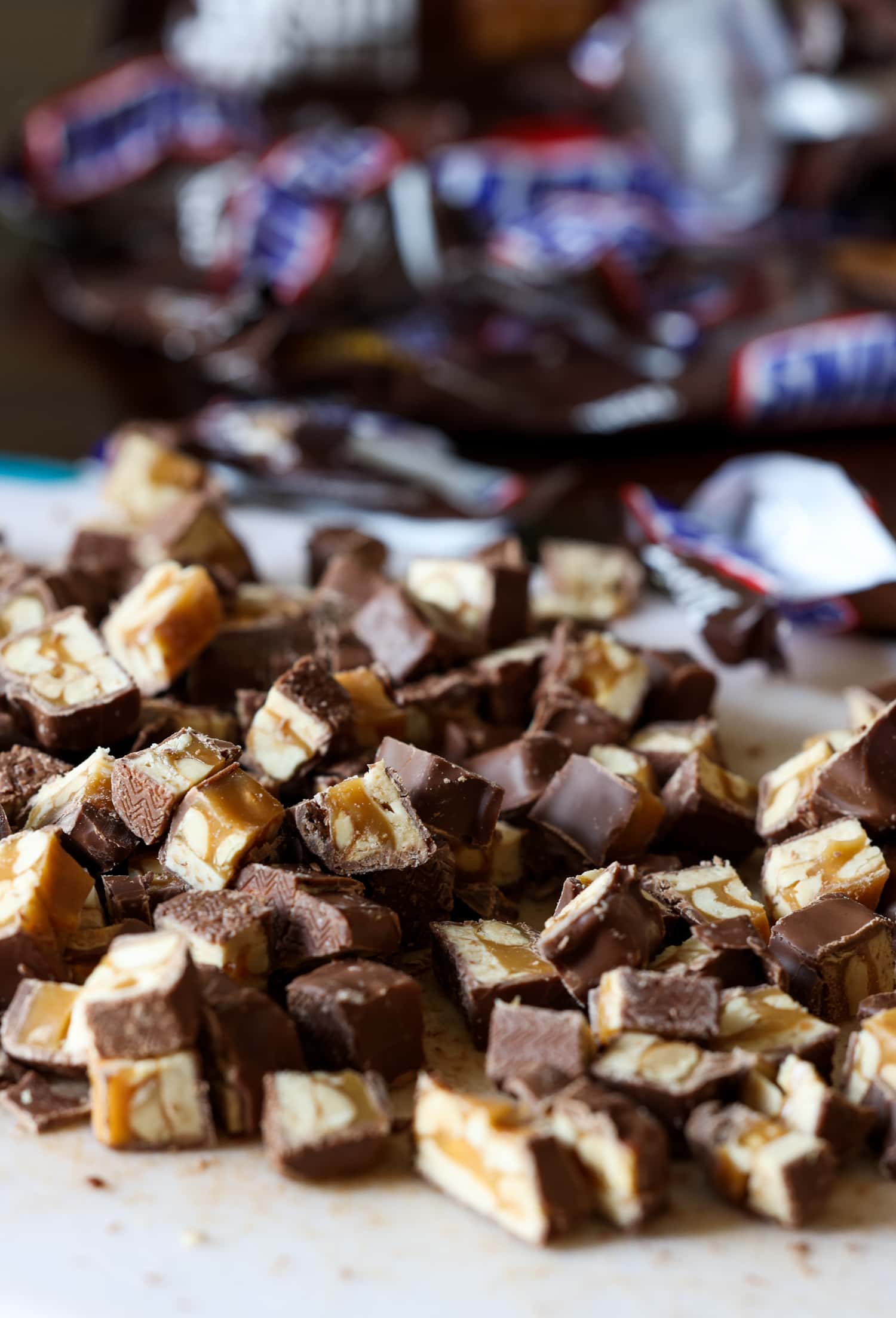 chopped snickers on a cutting board with wrappers in the background