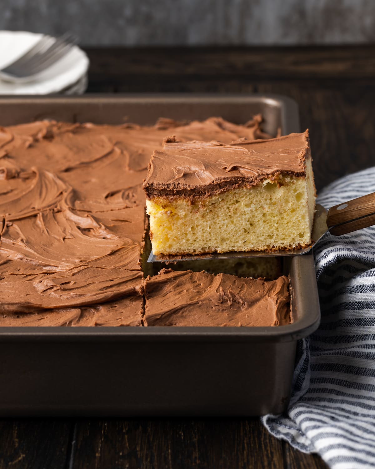 A slice of sour cream cake lifted from the rest of the cake in a baking pan.