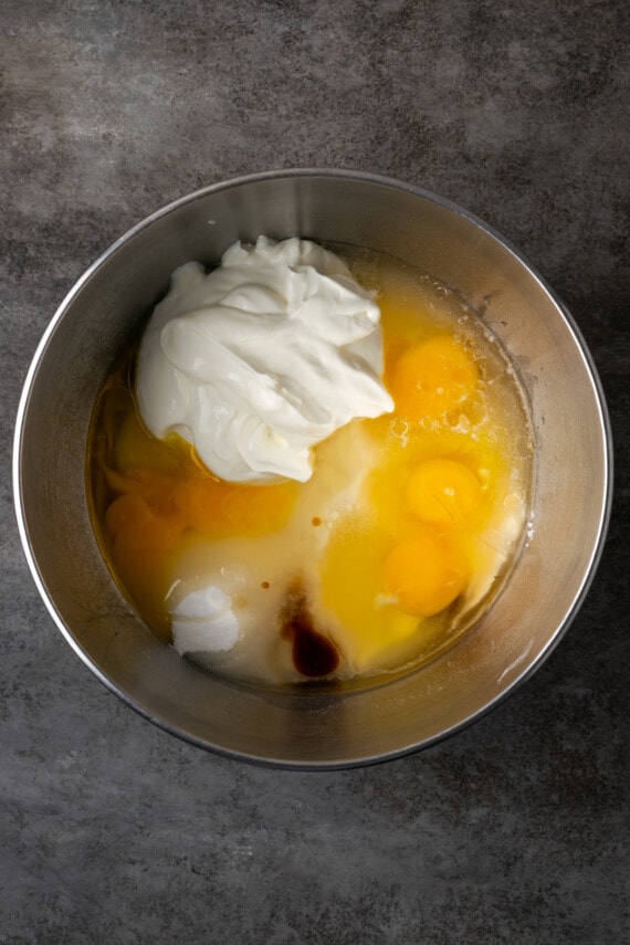 The ingredients for sour cream cake combined in a metal mixing bowl.