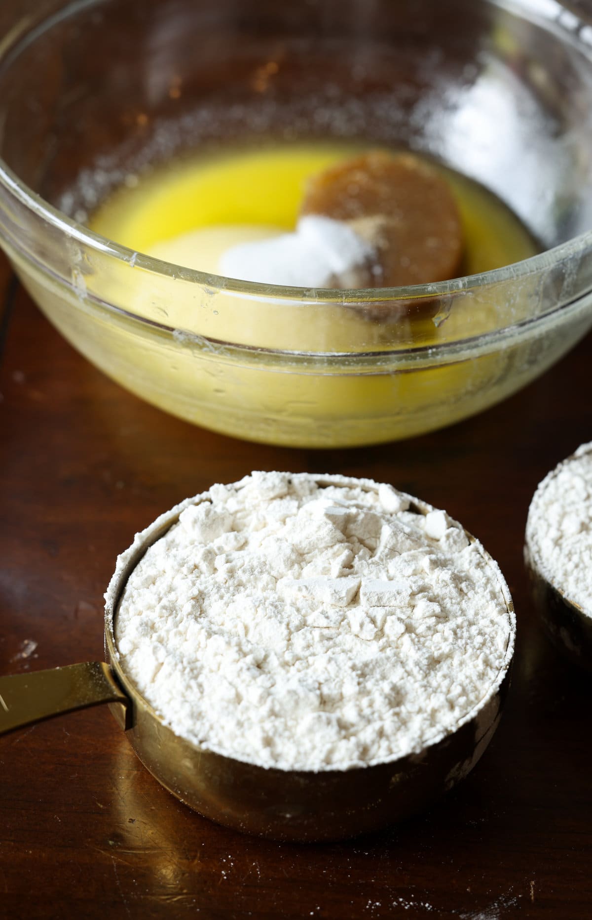 all purpose flour in a measuring cup in front of a bowl of melted butter and sugar.